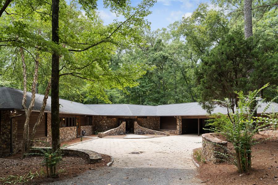The gravel approach to the stone lodge under hardwood canopy
