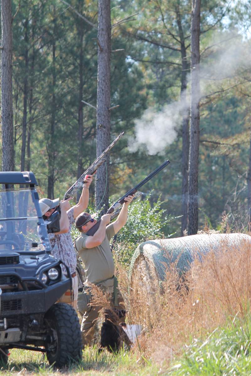 Shooters firing beside a utility vehicle with powder smoke hanging in the air